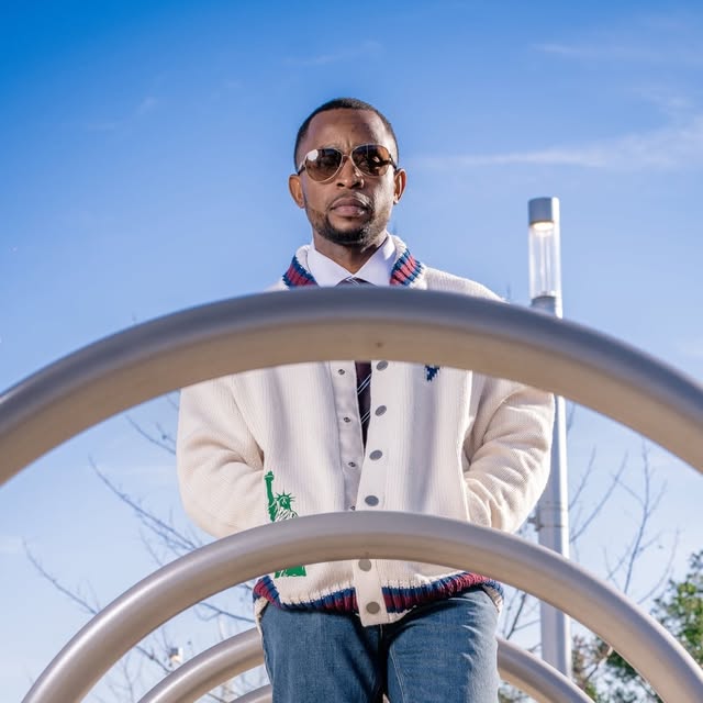 Editorial portrait of a man in a white cardigan against blue sky